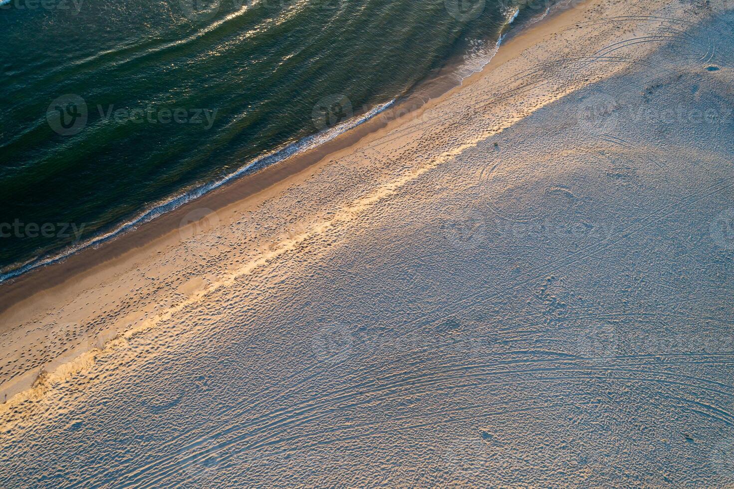 breathtaking aerial of turquoise waters, breaking waves, and remote sandy coast at sunset in summertime photo