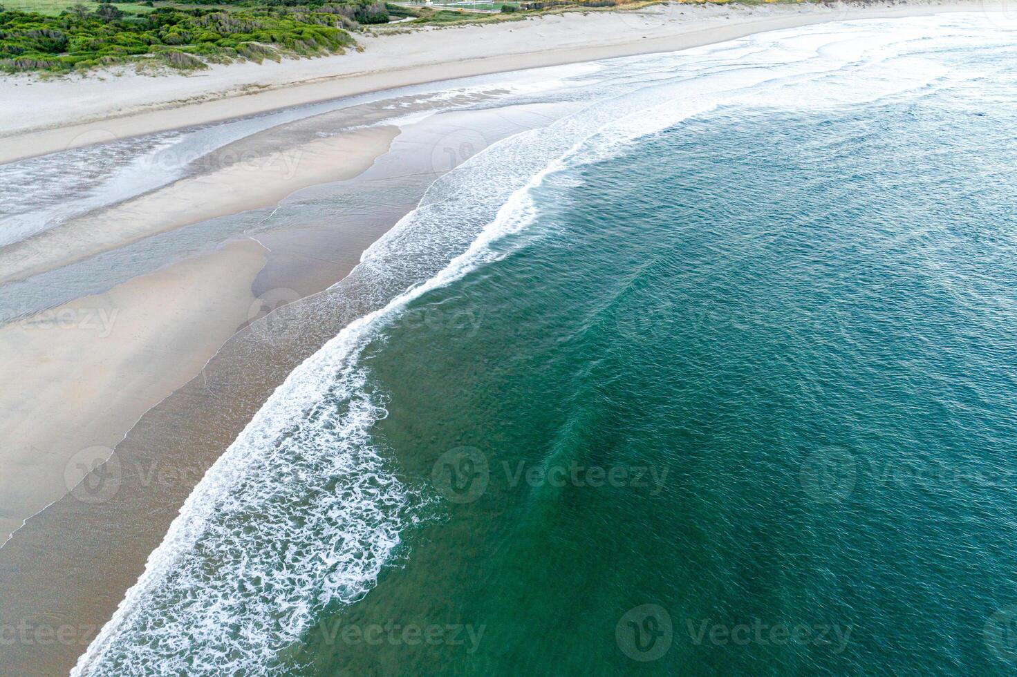 summer vacation destination empty beach with clear ocean waves and green vegetation aerial drone view photo