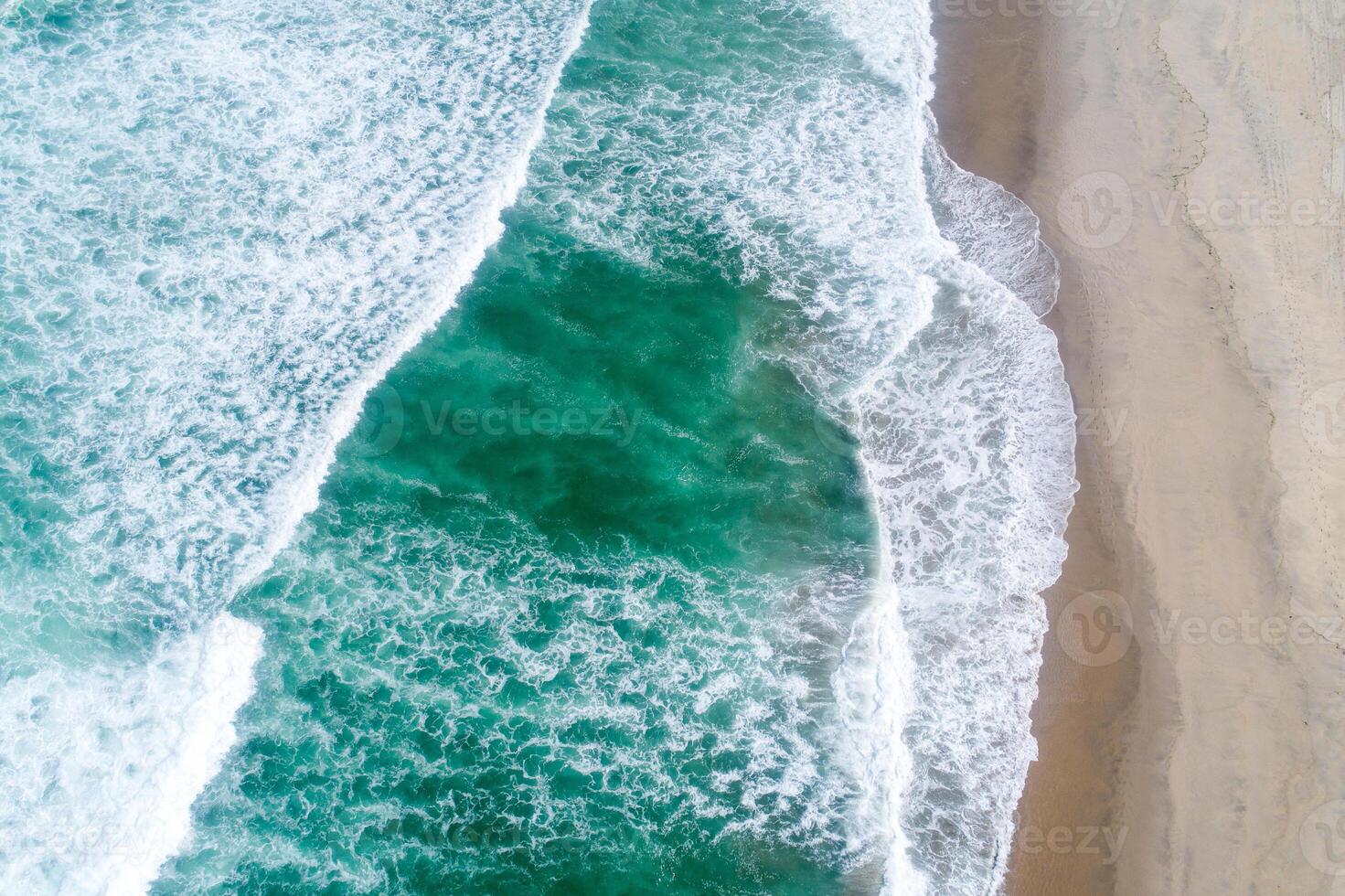 top down drone photography breaking surf on a wide beach with people Aerial image from a drone photo