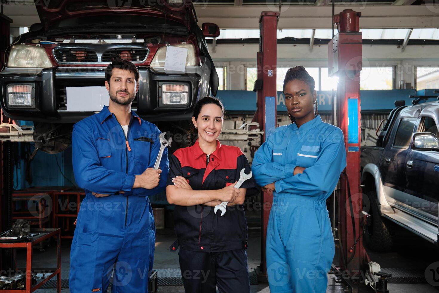 Harmonious professional mechanic teamwork, multiracial workers are rowing, cheerful, arms crossed and smile in fix car garage, maintenance service jobs in automotive transport industry station. photo
