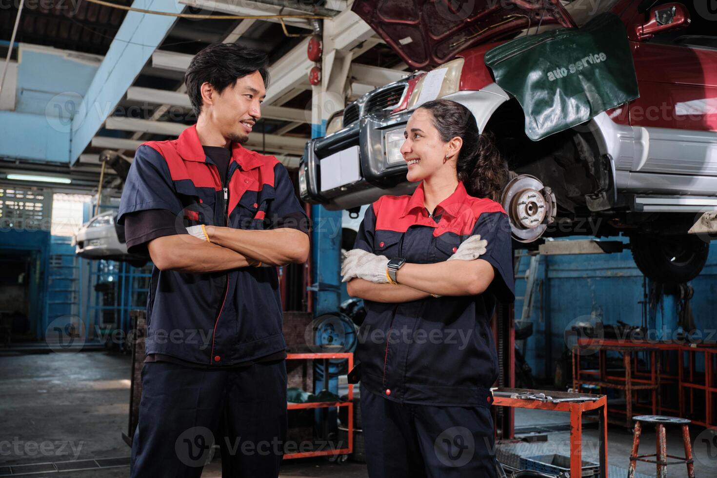 Happy professional teamwork, Latino female and Asian mechanic man workers are cheerful, looking together with smiles in fix car garage, and maintenance service jobs in auto transportation business. photo