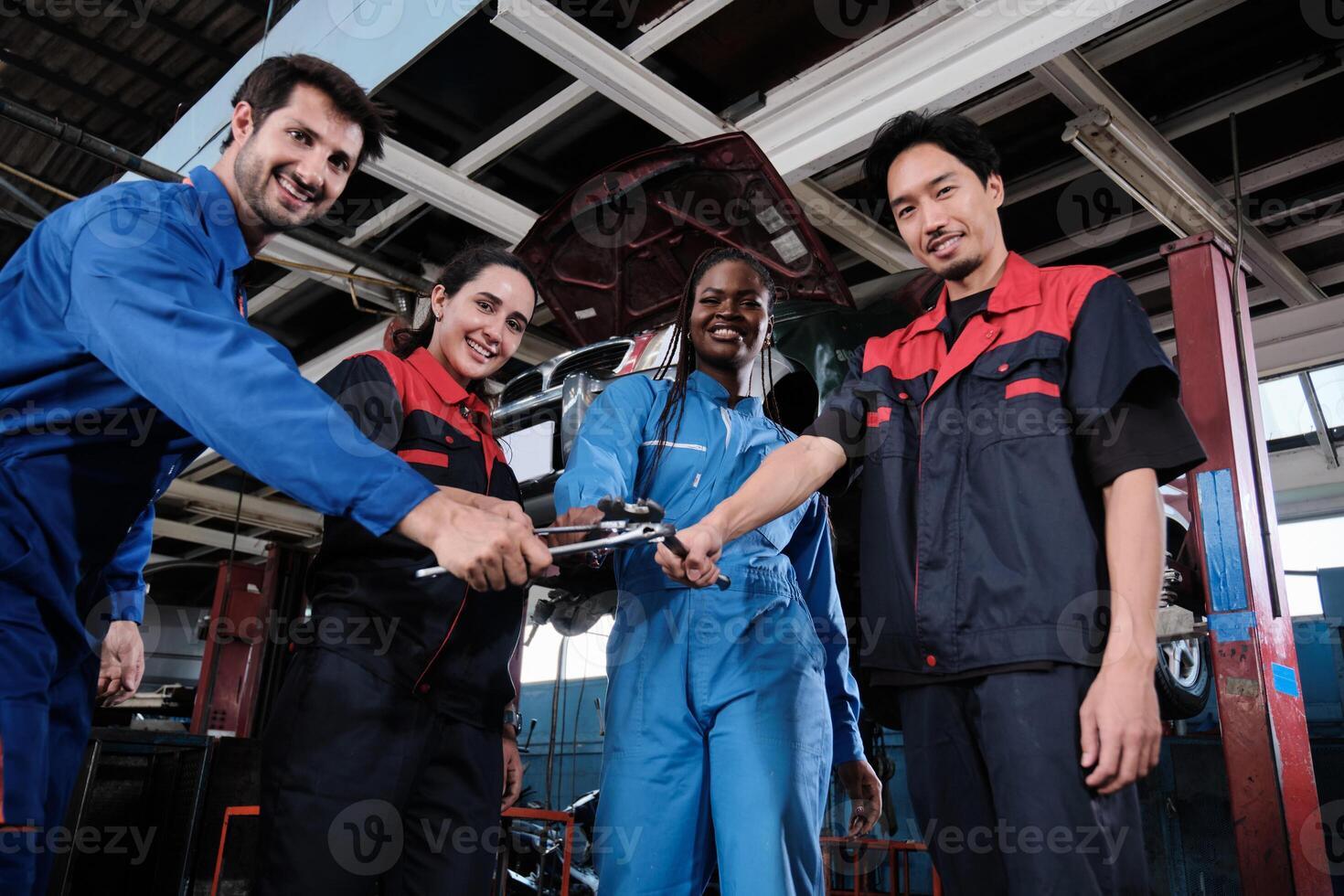 Harmonious professional mechanic teamwork, multiracial engineers with wrenches, cheerful, and happy smile in fix car garage, maintenance service jobs in automotive transport industry station. photo