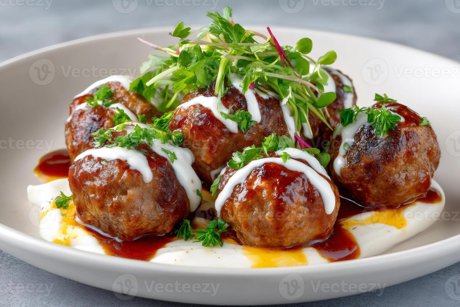 Delicious meatballs resting on yogurt sauce, garnished with microgreens and parsley photo