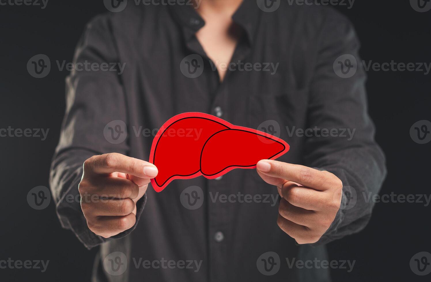 Man holding a symbol of a liver while standing against a black background photo
