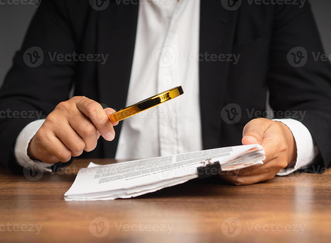 Businesswoman holding a magnifying glass and looking at reading documents while sitting in the office. photo
