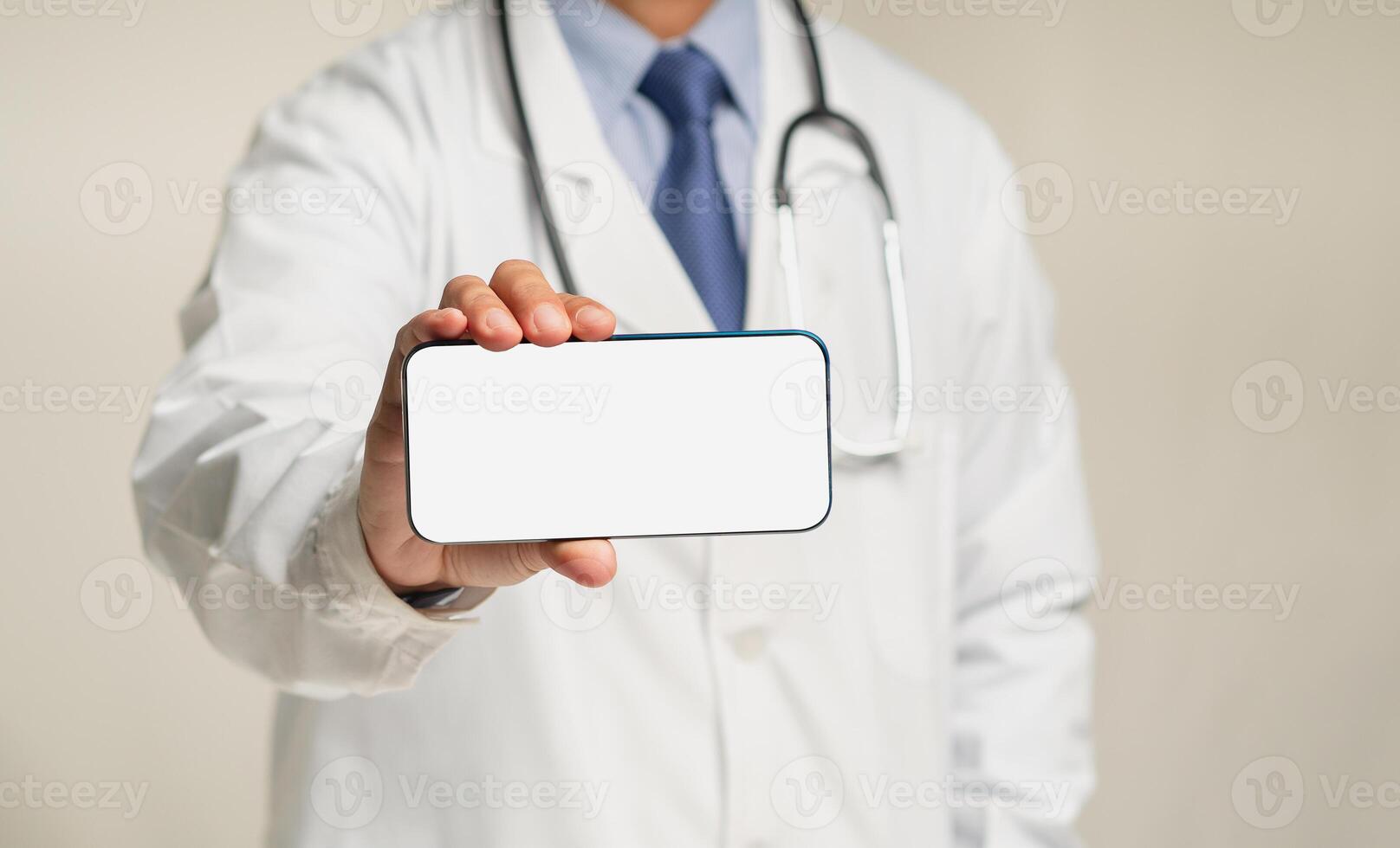 A doctor is holding a white blank screen smartphone while standing in the hospital photo