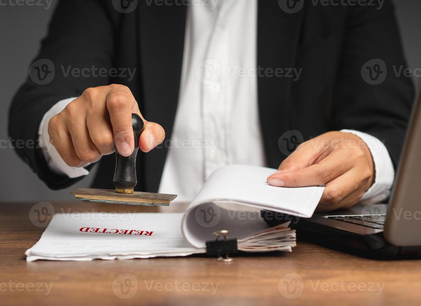 Businessman stamped rejected on a document while sitting in the office photo