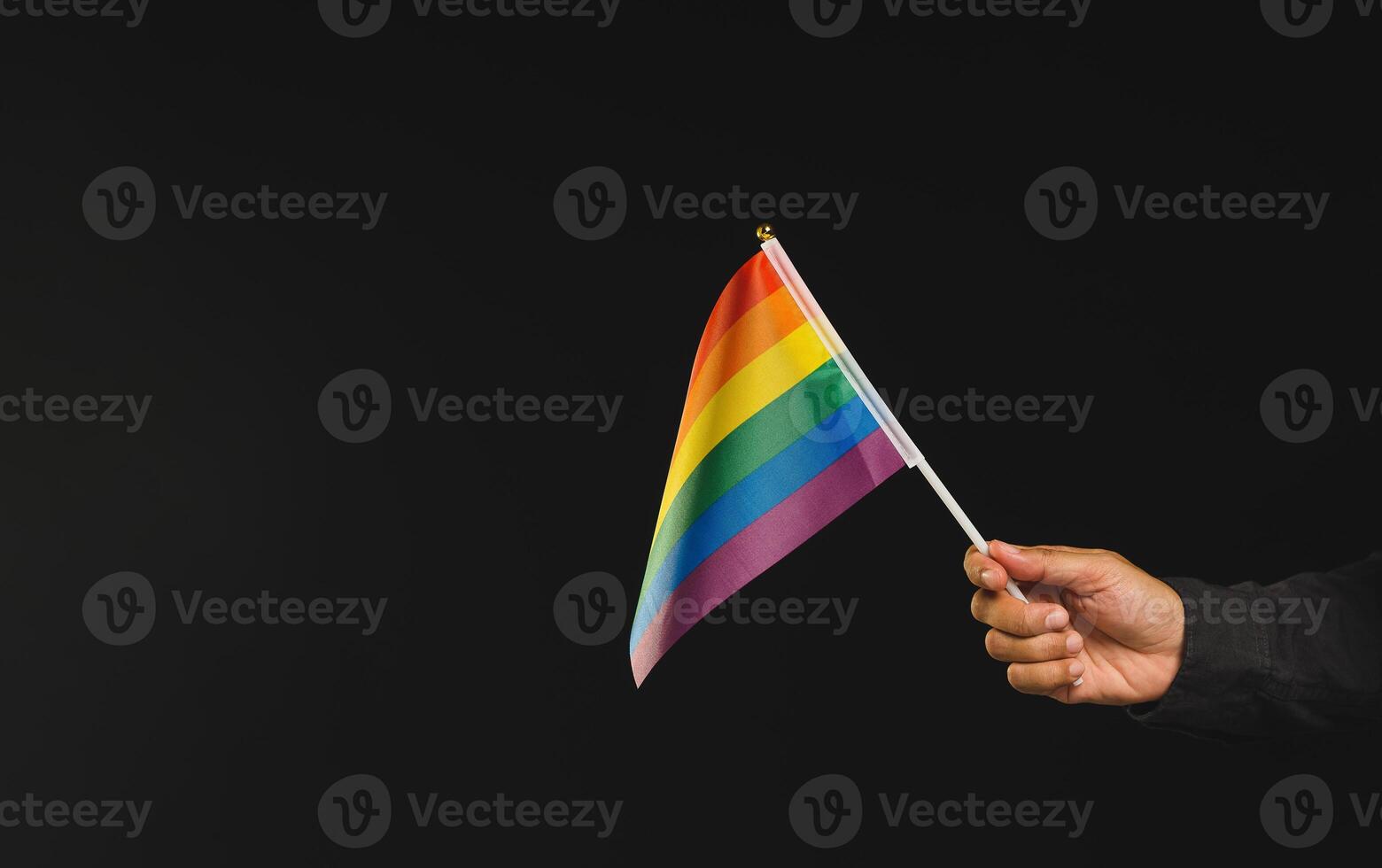 Rainbow flag showing in hand against a black background photo
