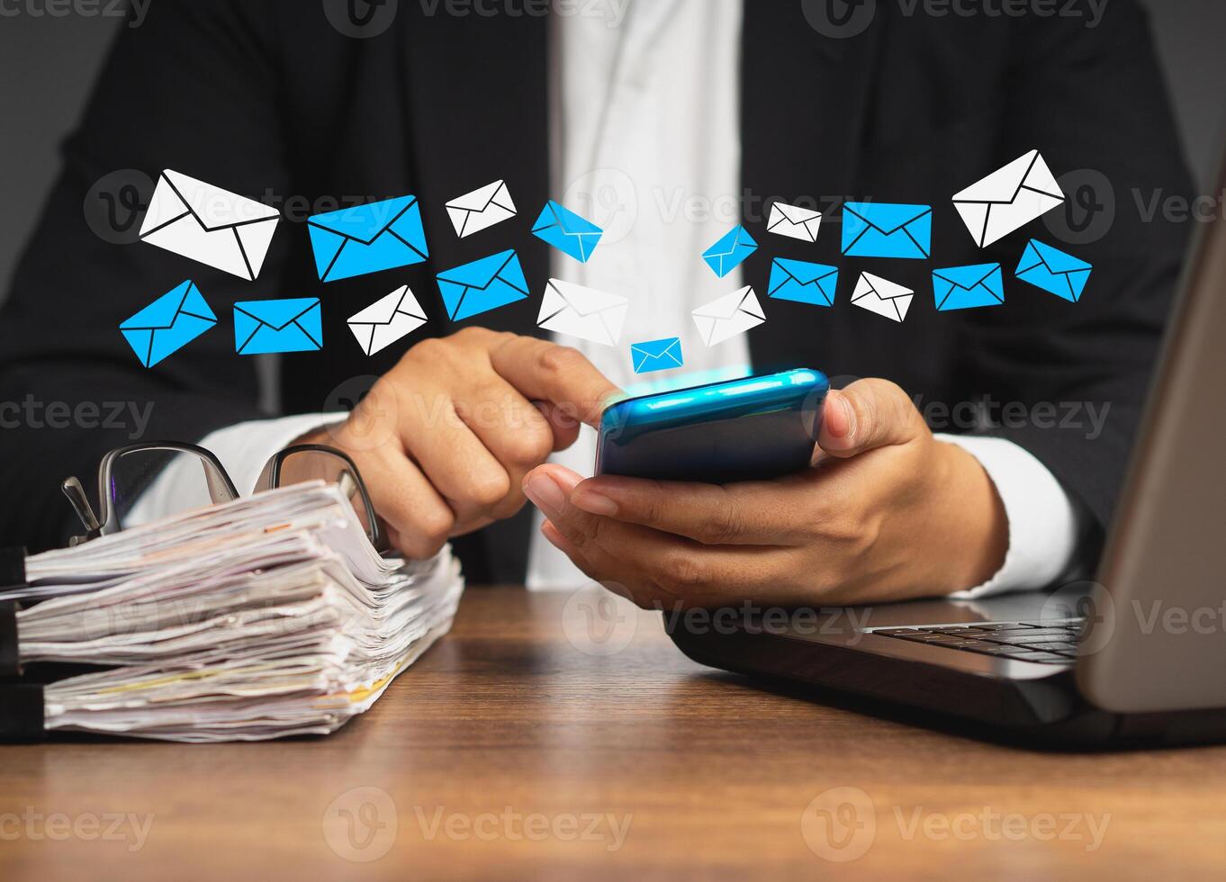 Businesswoman using a smartphone receives a new message with email icons while sitting at the table. photo
