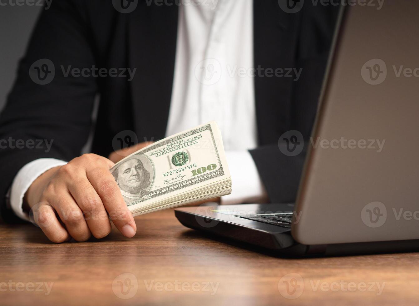 Close-up of a businessman in a suit holding US dollar bills while sitting in the office. photo