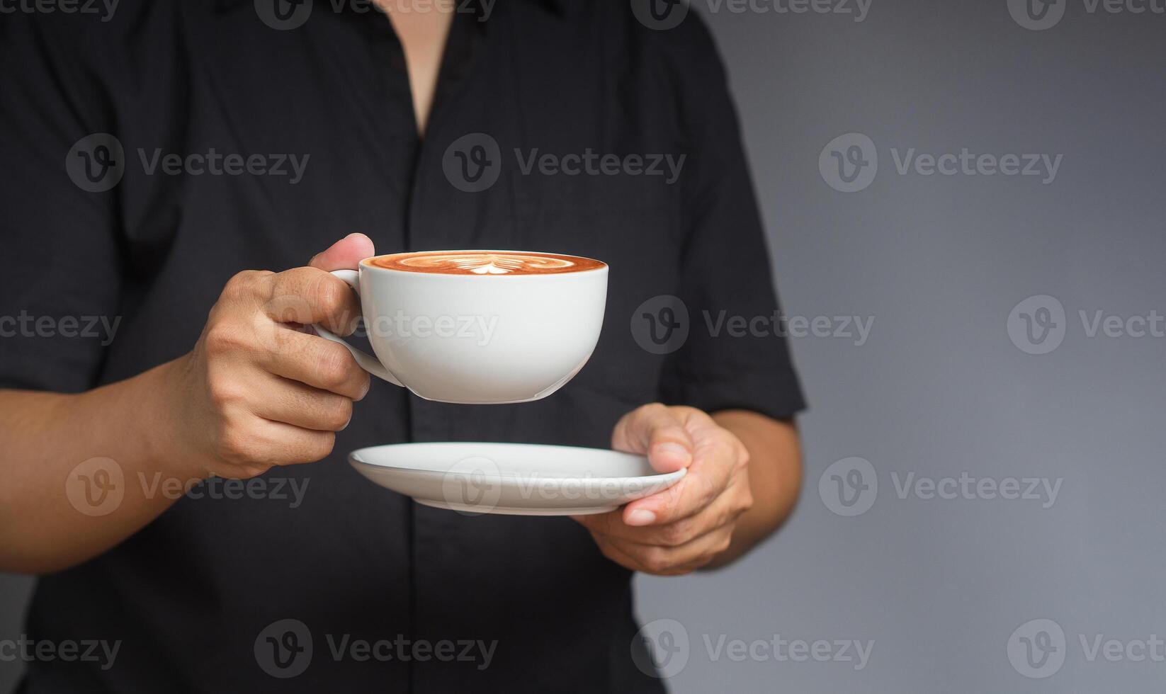 Close-up of hands holding a coffee cup while standing against a black background photo