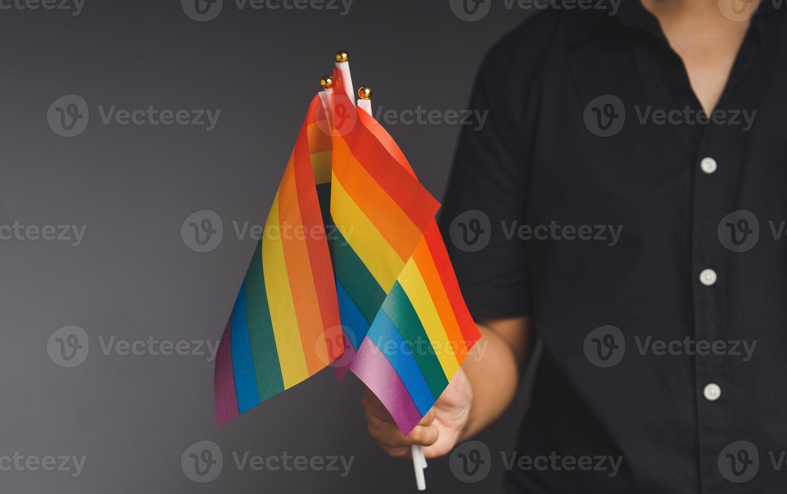 Rainbow flags showing in hand ont a black background. photo