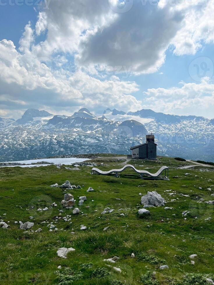 Wooden sun lounger in the mountains with a chapel in the background. Five Fingers Viewpoint in the Austrian Alps photo