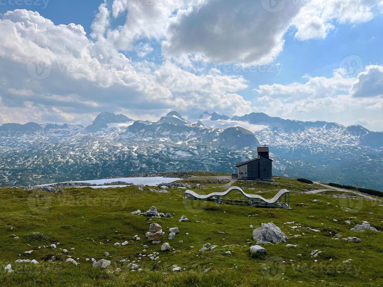 Wooden sunlounger in the mountains with a chapel in the background. Five Fingers Viewpoint in the Austrian Alps, Obertraun photo
