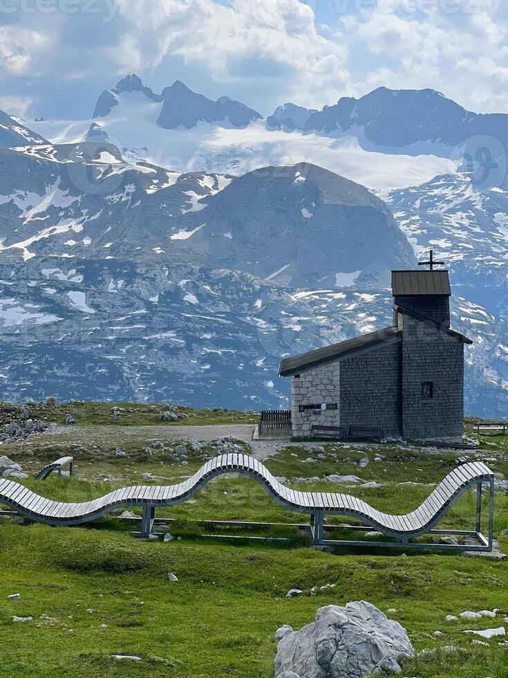 Wooden sun lounger in the mountains with a chapel in the background. Five Fingers Viewpoint in the Austrian Alps, Obertraun photo