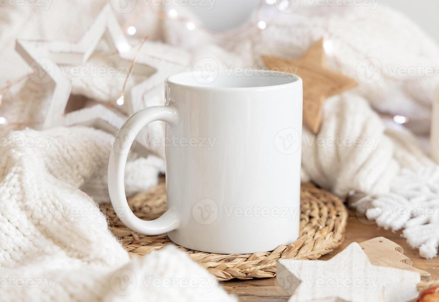 White coffee mug near white sweater and wooden Christmas decor and lights, holiday mockup, copy space photo