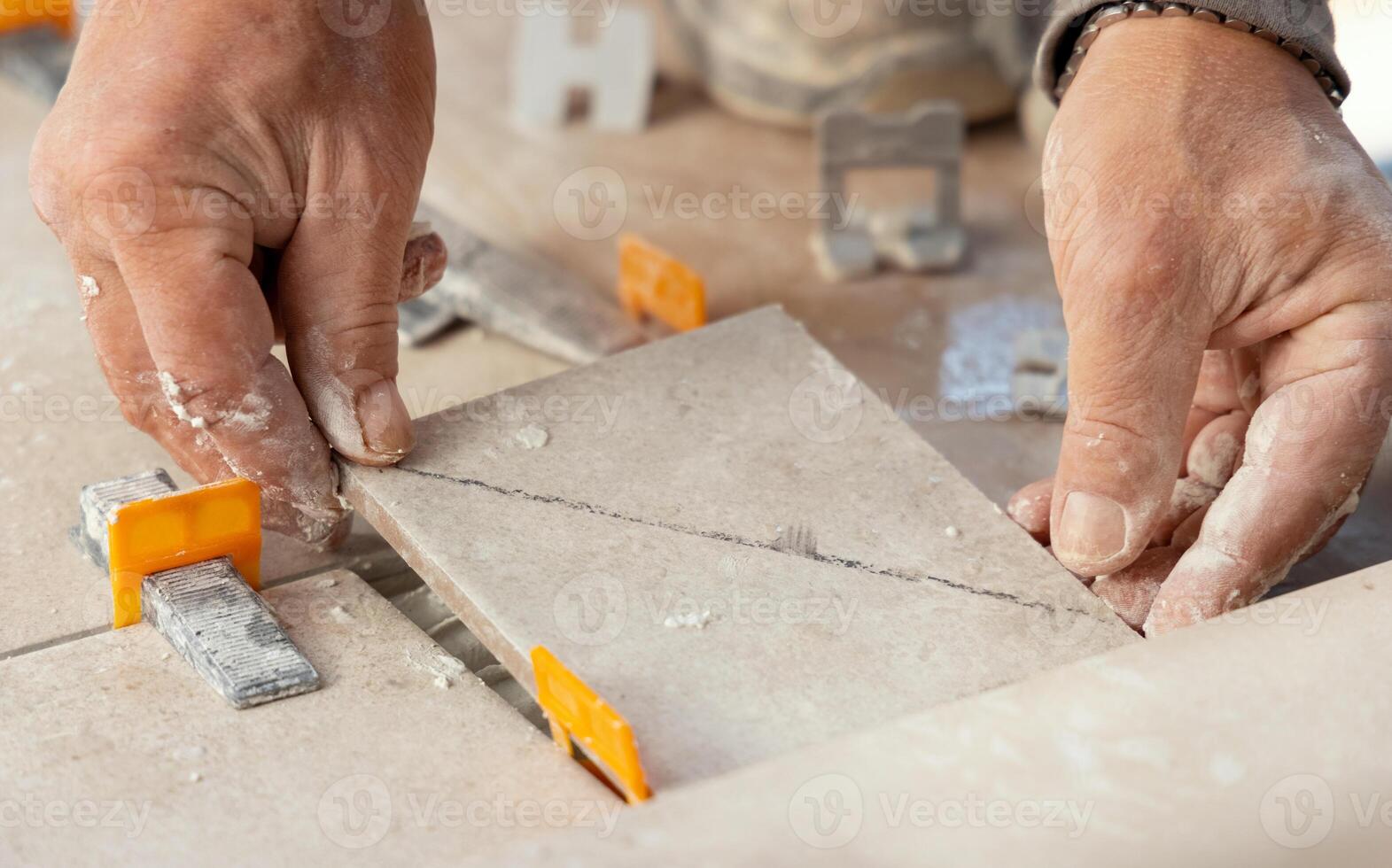 Tiler laying the ceramic tile on the floor with dusty hands. Home renovation or building new house photo