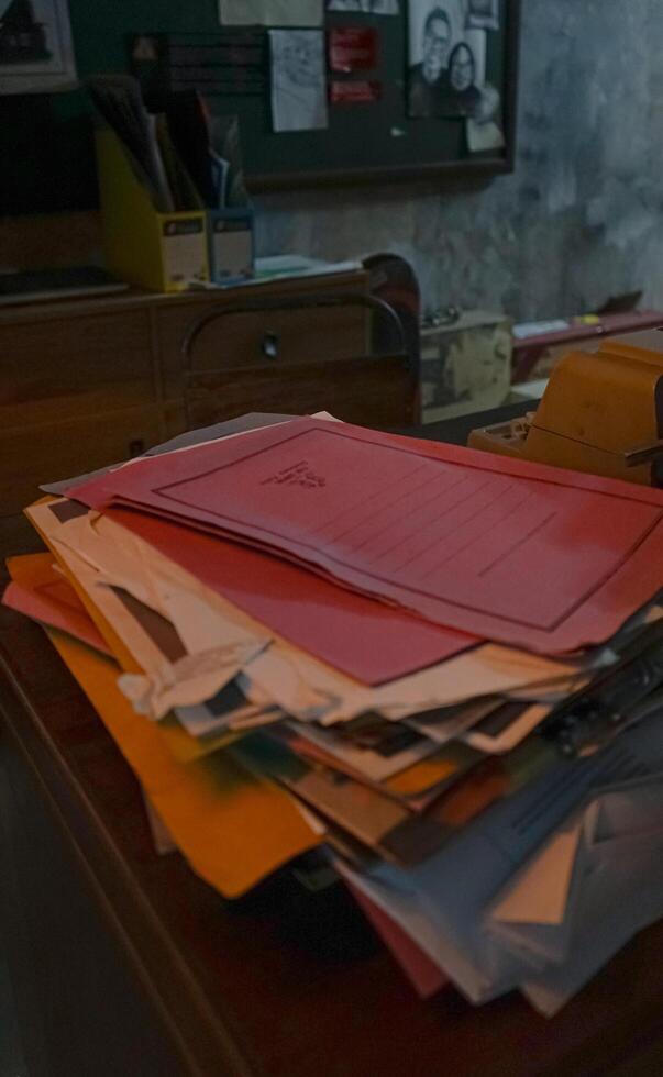A pile of papers on a desk in a dark room photo
