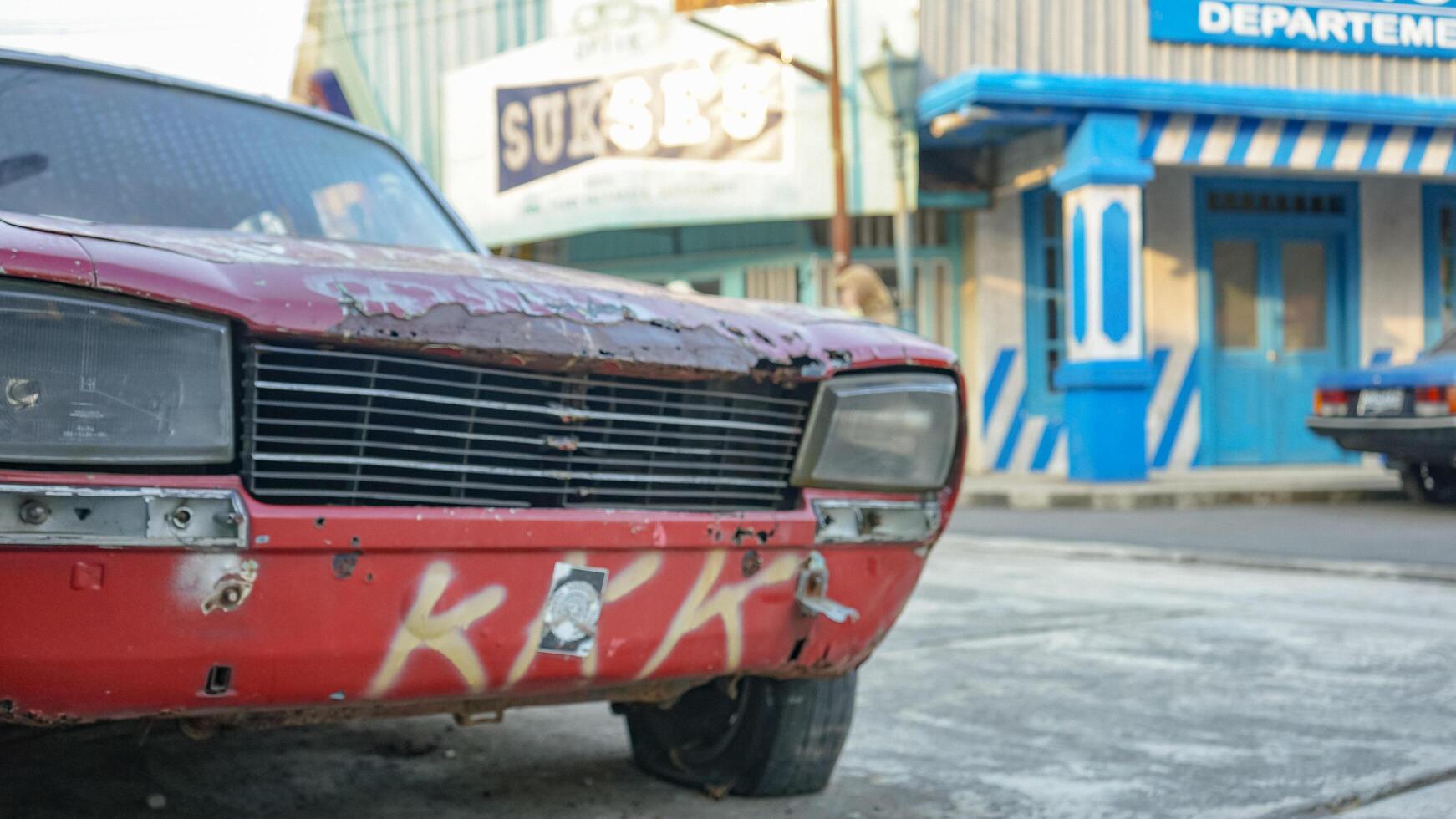 A severely weathered red car with graffiti on the front photo