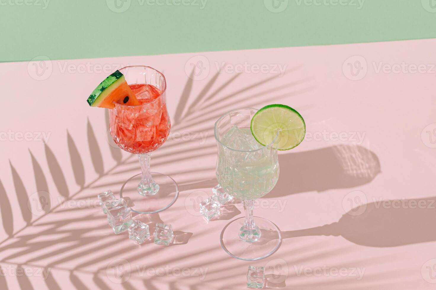 Summer scene with refreshing watermelon and lime drinks and palm leaves shadow on pink and green background. Sun and shadows. Minimal cocktail concept. Trendy summertime party idea. Summer aesthetic. photo