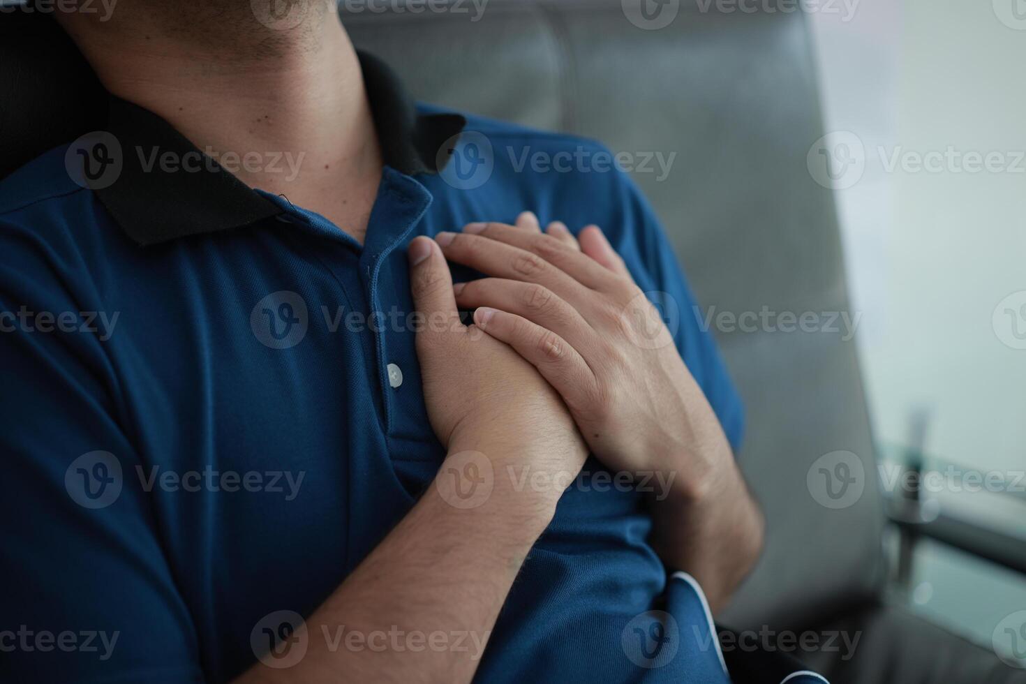 a man is holding his chest while sitting on a couch photo