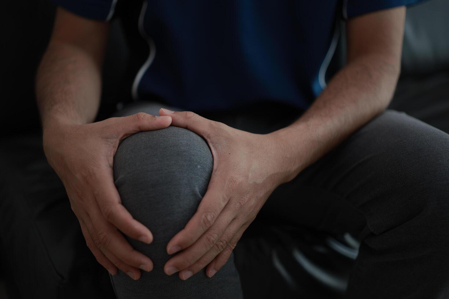 Closeup of a man sitting on a couch with his knee in pain photo