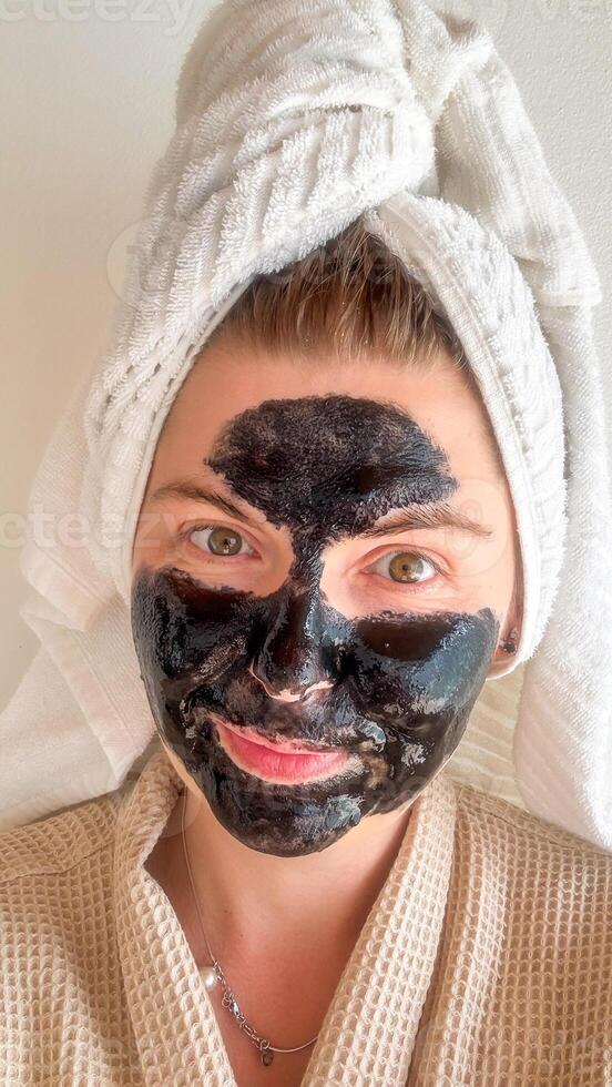 A woman of Caucasian descent in a waffle robe and charcoal mask, embracing Hygge serenity and National Relaxation Day photo