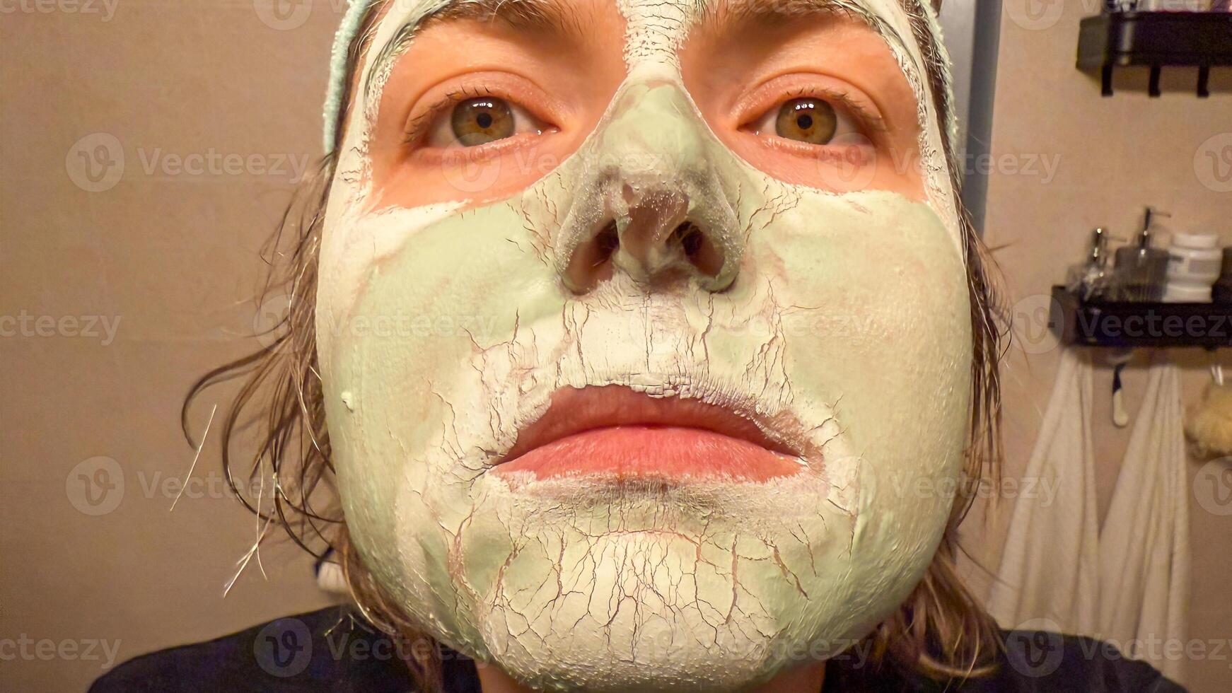 A Caucasian womans face, adorned with a cracked mint mask, echoes self care rituals and World Spa Wellness Day photo