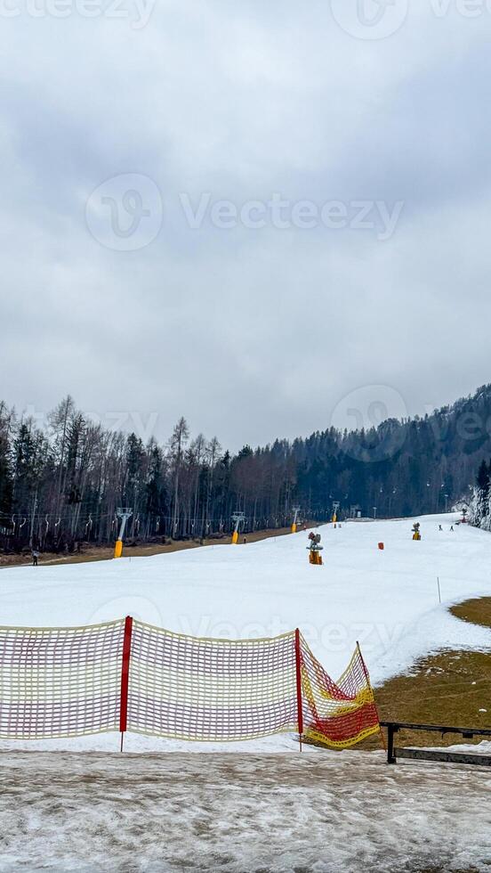 Snow draped ski slope whispers of frosty Imbolc celebrations, with solitary netting beckoning alpine wanderers into winters serene embrace photo