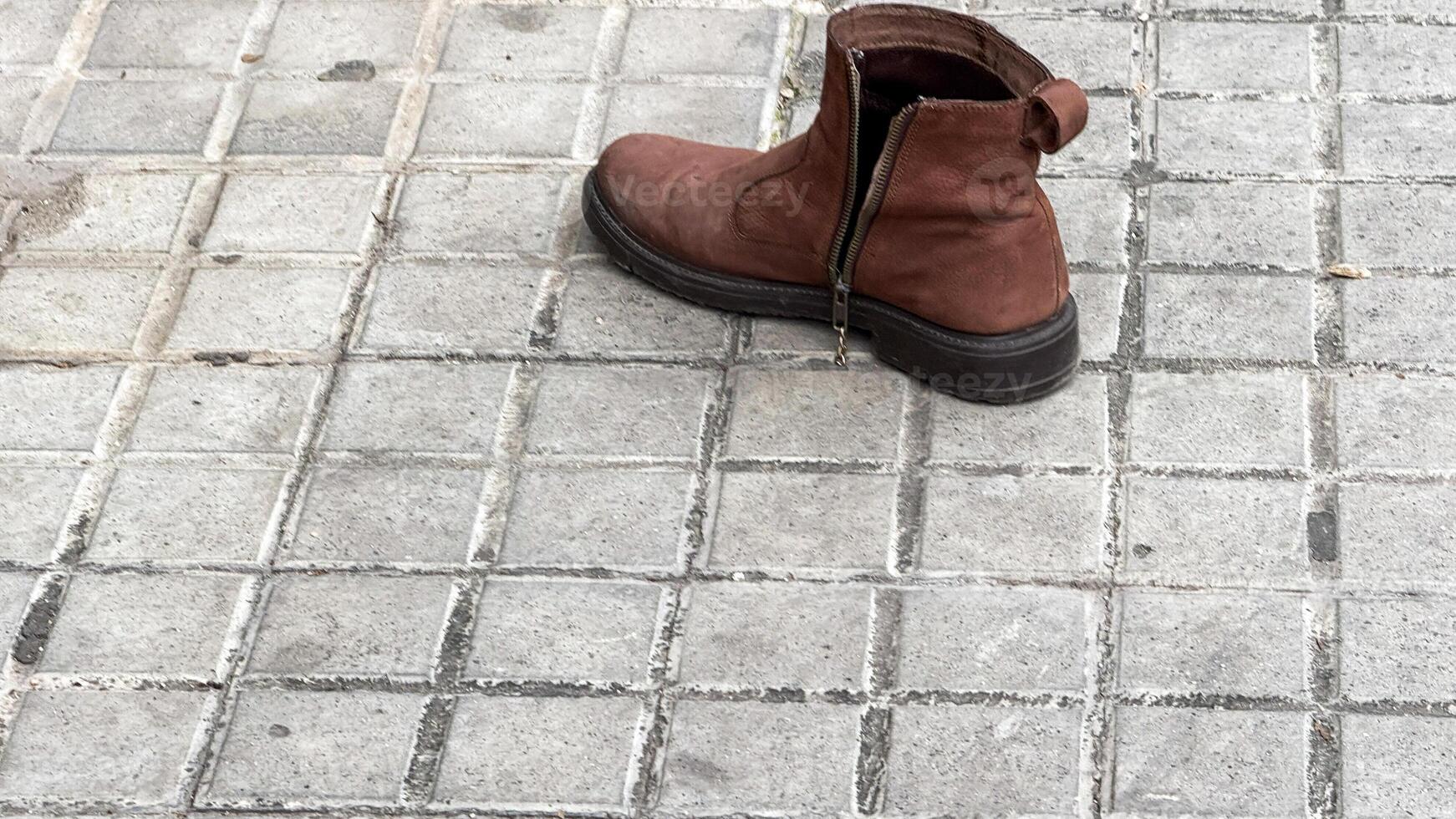 Lonely leather boot on cobblestone whispers wanderlust tales, evoking lost and found themes and celebrating International Left Handers Day photo