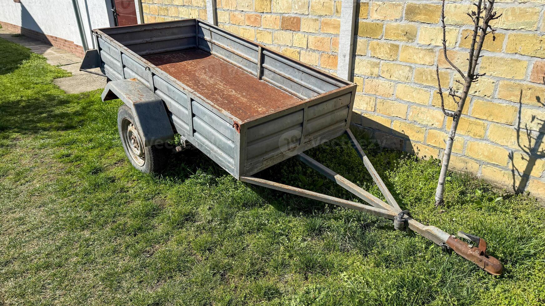 Rustic metal trailer basks in spring sunlight, hinting at whimsical backyard projects or Dia de la Cosecha festivities photo