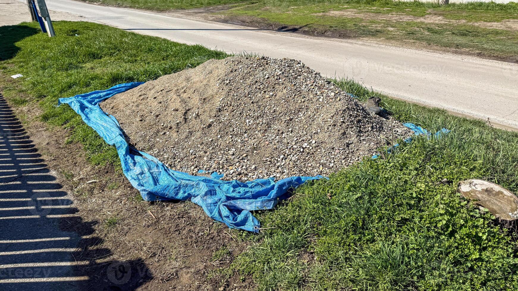 A mound of gravel atop a cerulean tarp whispers construction secrets of Beltane festivities and groundhog seances photo