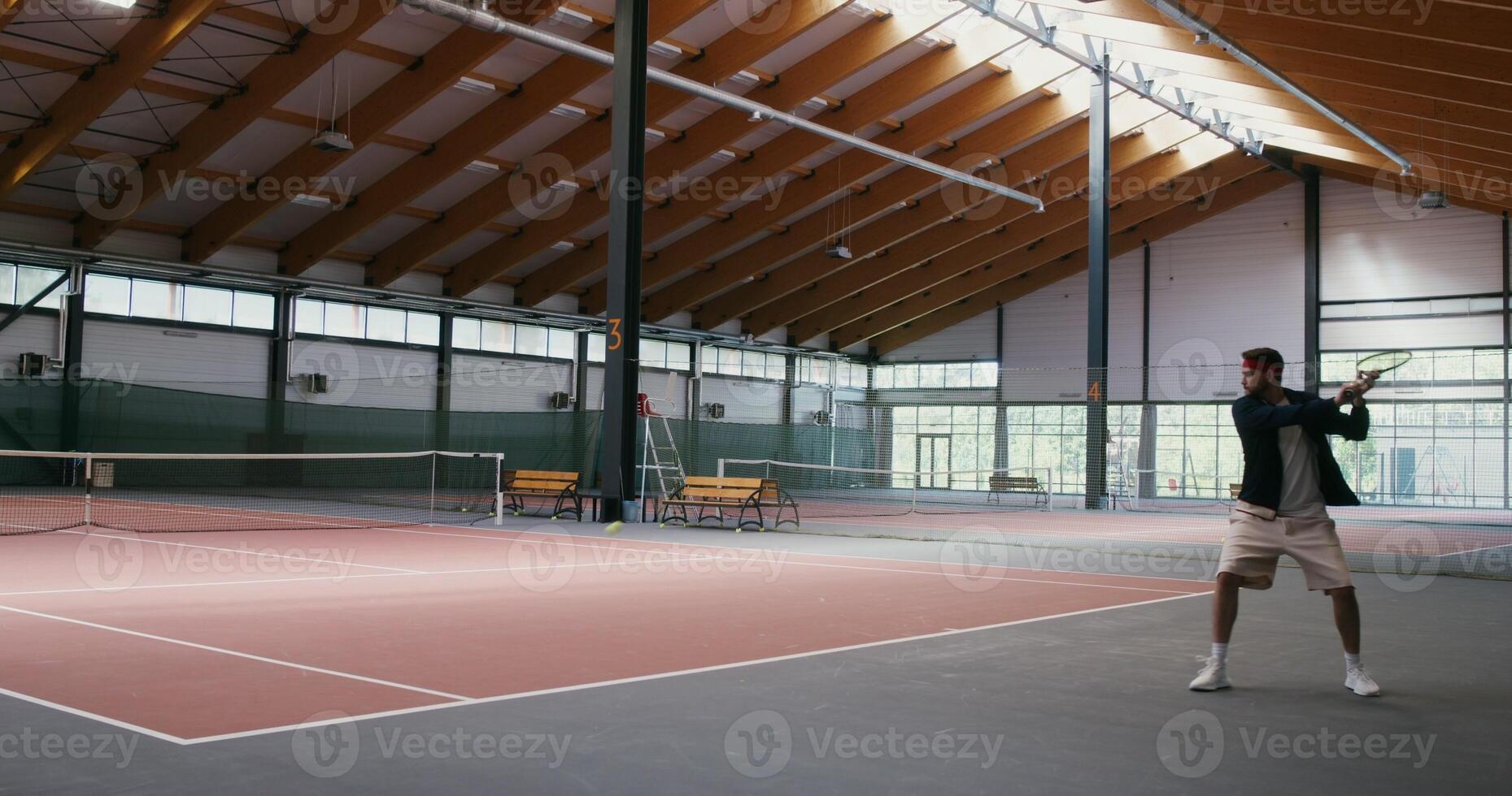 Young man and woman playing tennis on an indoor tennis court, bouncing the ball with a racket until the man loses a round by failing to throw the ball over the net photo