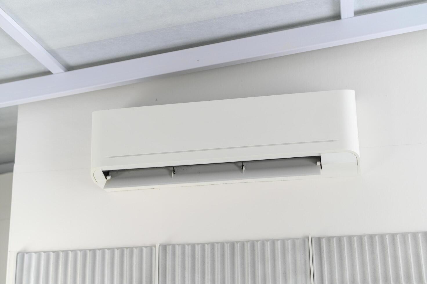 Offering comfortable cooling and climate control, modern white air conditioner unit sits mounted wall indoors. essential technology provides relief from heat, creating pleasant environment photo