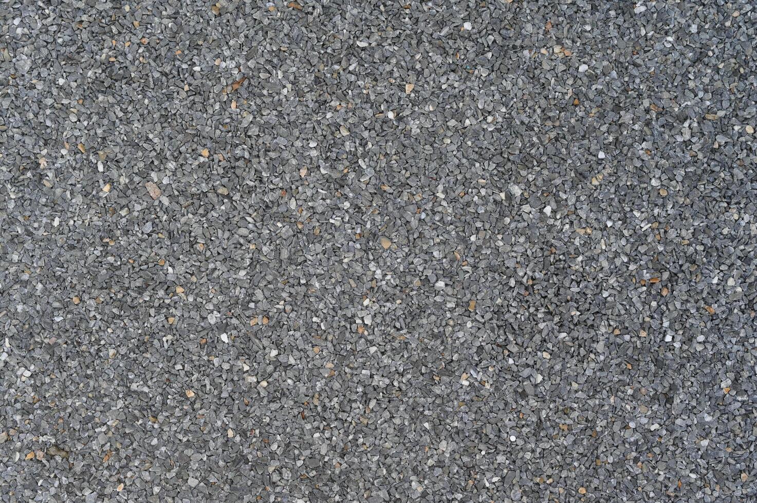 Granular dark grey abrasive texture forms detailed close up surface background. Uniform rough pattern material appears across full frame ideal for graphic design photo