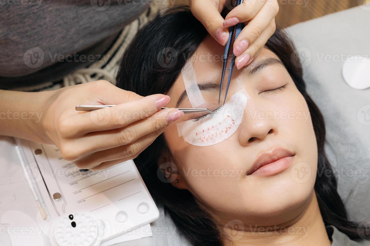 Young southeast asian woman finds peace during beauty salon procedure applying eyelash extension. Meticulous work enhances eyelashes eyes beauty through cosmetic extension promoting health photo