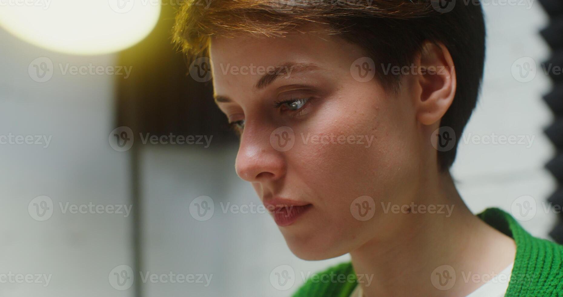 Side view of the face of a young woman of European appearance with a short haircut, with a concentrated look working at the computer, close up photo