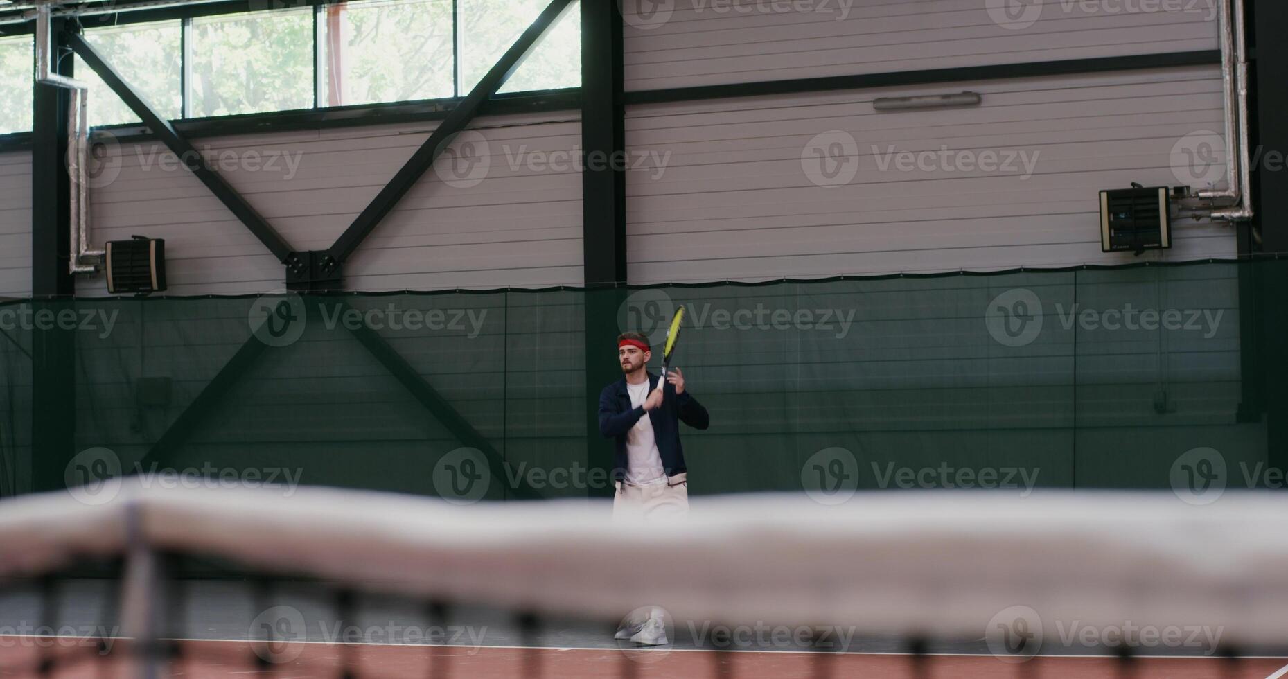 A young dark haired man of European appearance plays big tennis, hitting the ball with a racket over and over again, gracefully bouncing with each racket hit photo