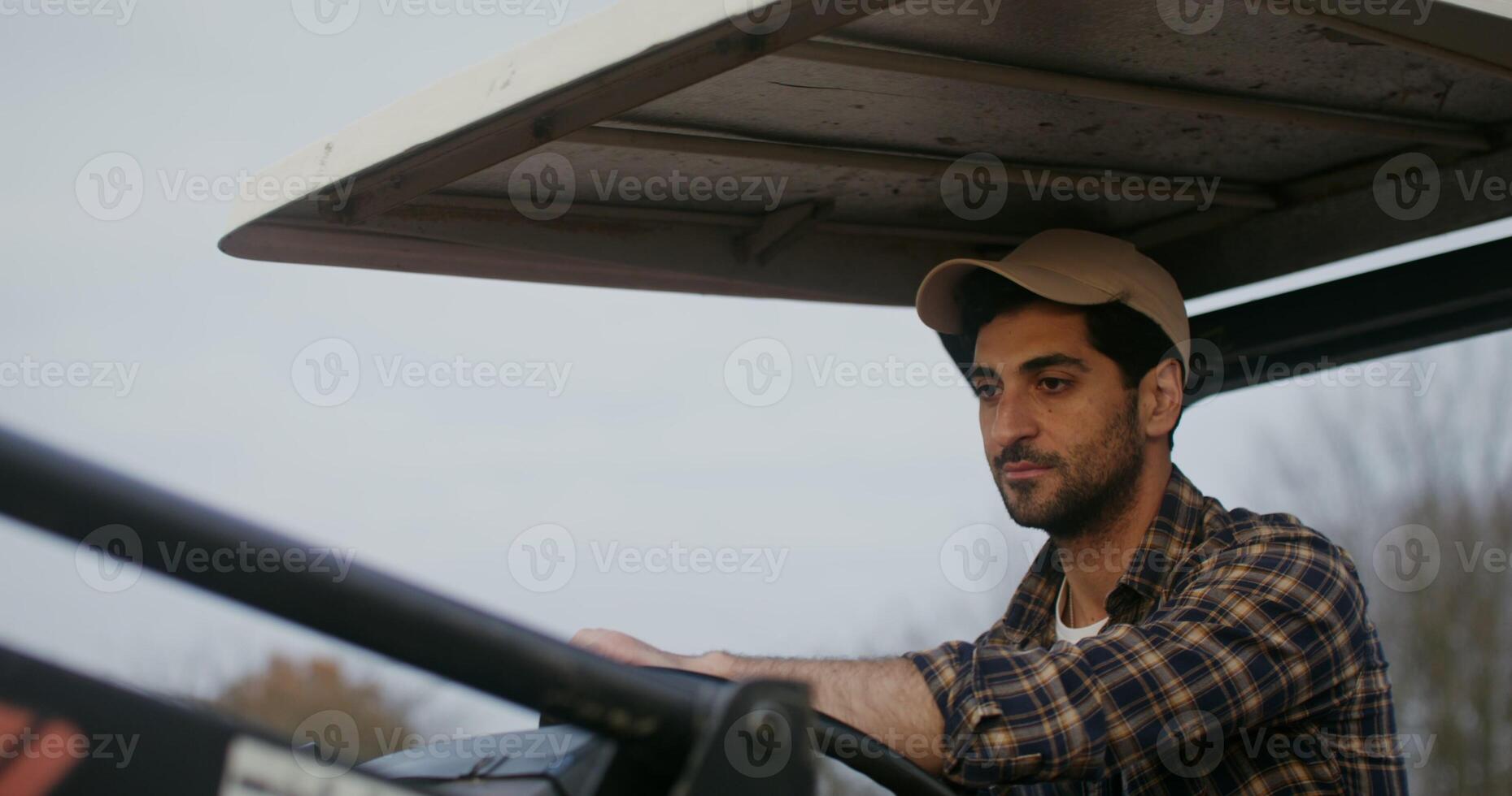 A young male farmer of European appearance rides an agricultural tractor with an open cabin, plowing a field on an autumn day, videography of the details of the work close up photo