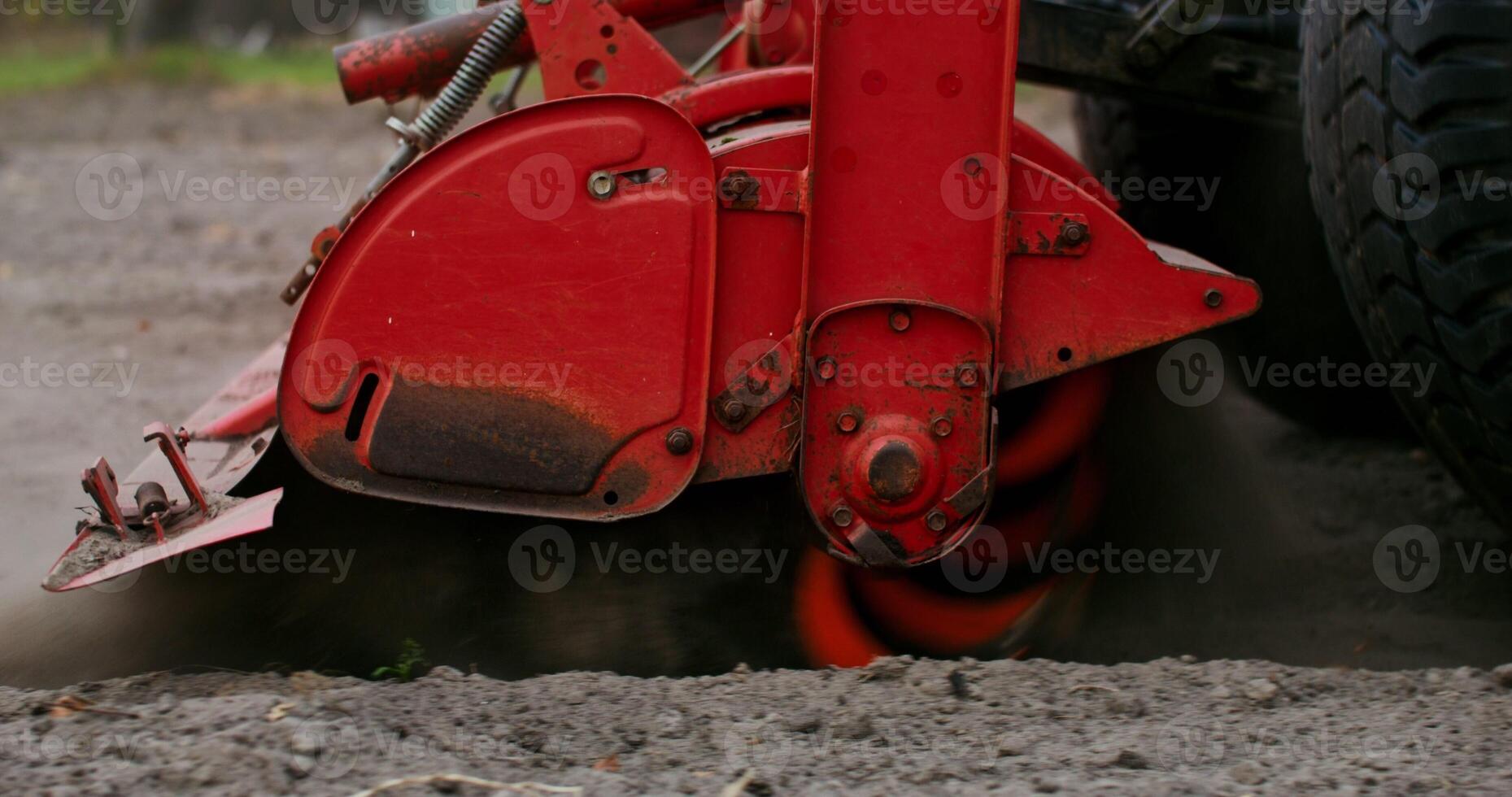 The lowered plow of an agricultural machine is spinning fast, plowing the land, close up, no people in the photo