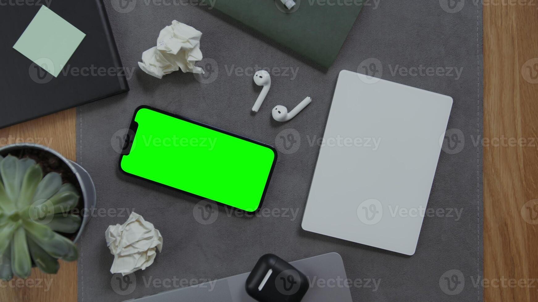 A man's hand lies on a blank sheet of a notebook, next to a mobile phone with a green screen and crumpled sheets of paper, close up. Mockup, chroma key, copy space photo