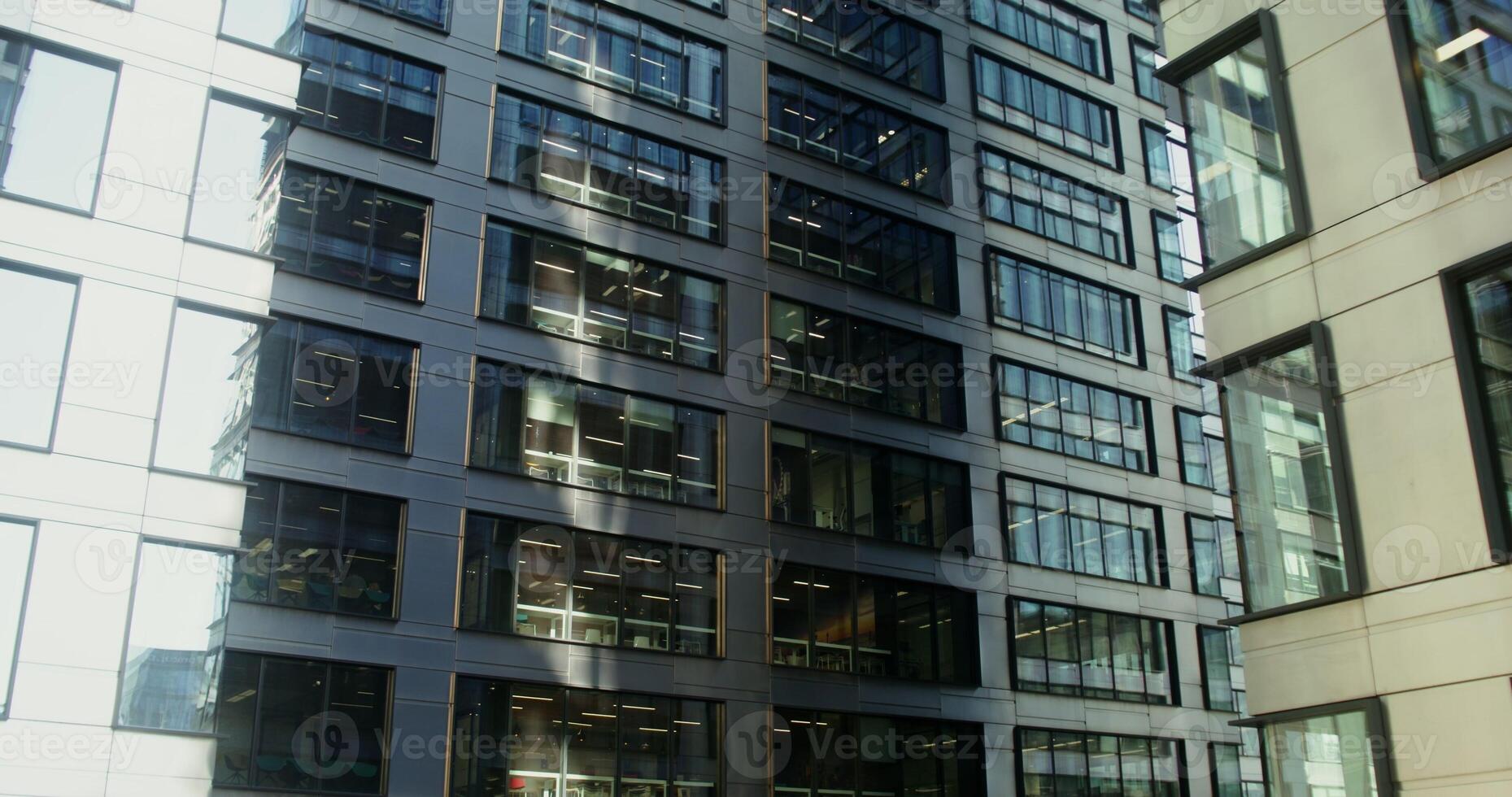 High rise office building with large stained glass windows. Business center of the modern city. Light in the windows of office workers. in 4k, red komodo photo
