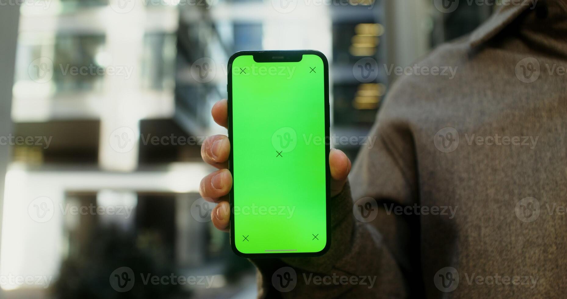 Close up of a mobile phone with a screen forward in the hands of a young man, no face. Copy space, green screen, chroma key, mockup. in 4k, red komodo photo