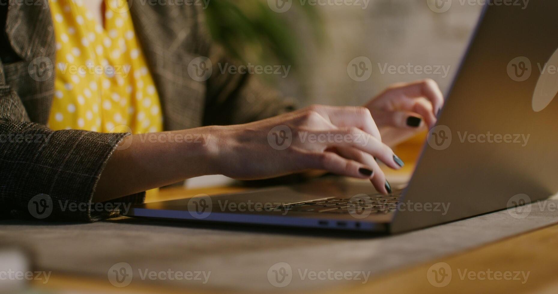 Businesswoman of European appearance with short hair is typing on a laptop, a close up of her hands with black manicure smoothly transitions to the view of her centered face photo
