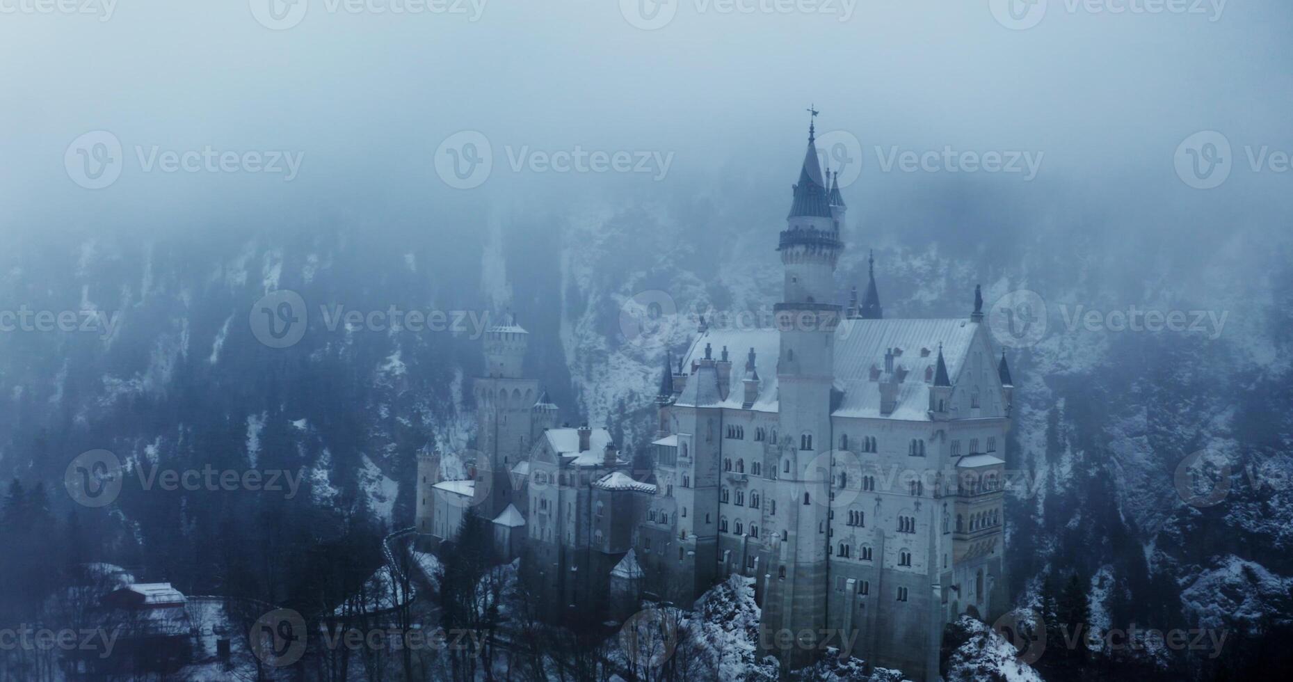Overview of Hohenzollern Castle from a dynamic motion quadcopter, bird's eye view close up footage on a winter day. Foggy haze over castle, located on top of a hill overgrown with spruce forest photo