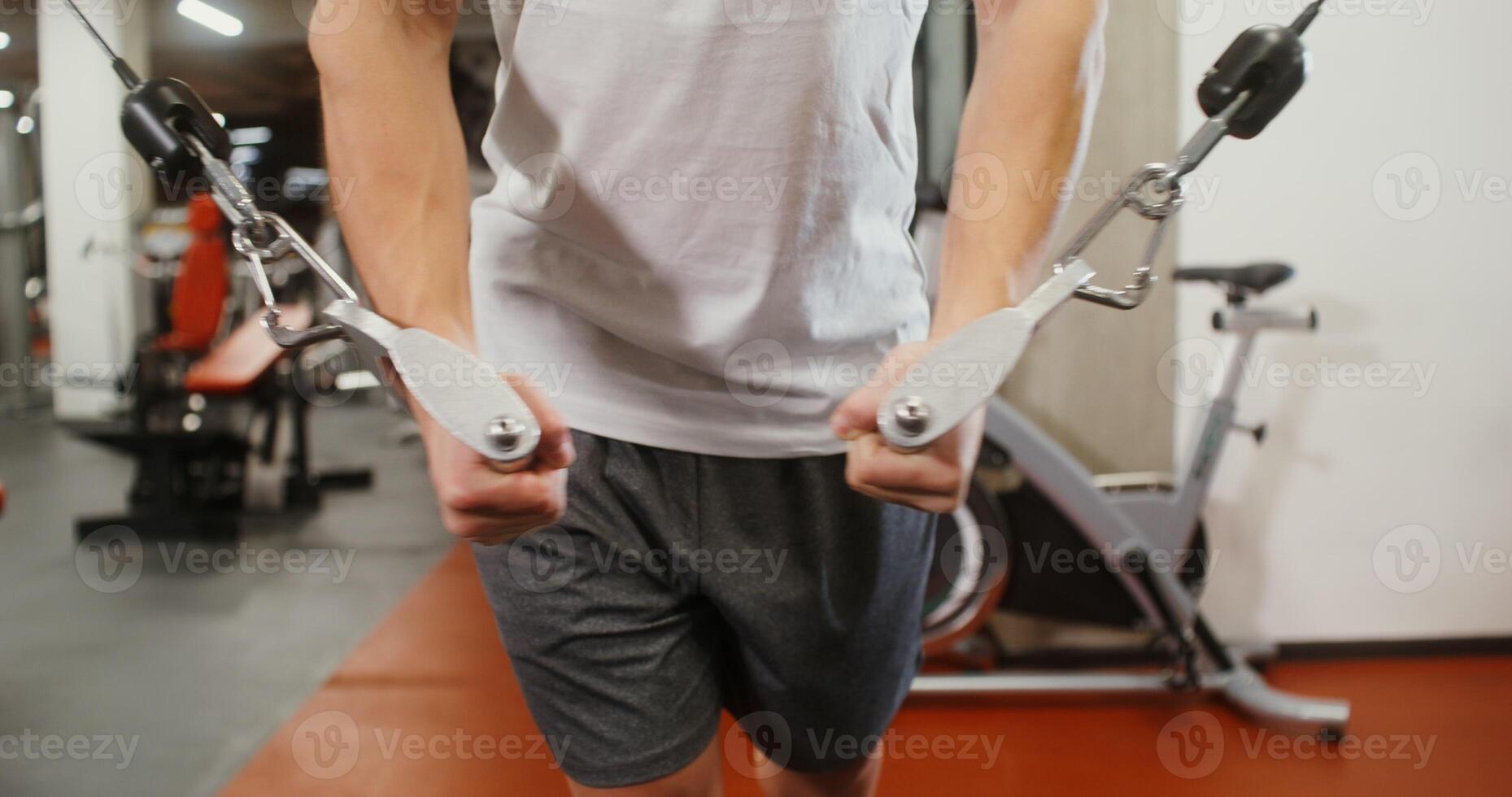 Front view, close up of male hands pushing down the levers of the exercise machine lifting weights, the man's face is not visible, unidentified identity photo
