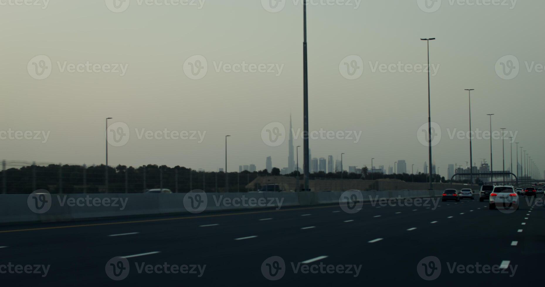 Busy highway on the outskirts of a modern metropolis with glass skyscrapers in the rays of the setting sun photo