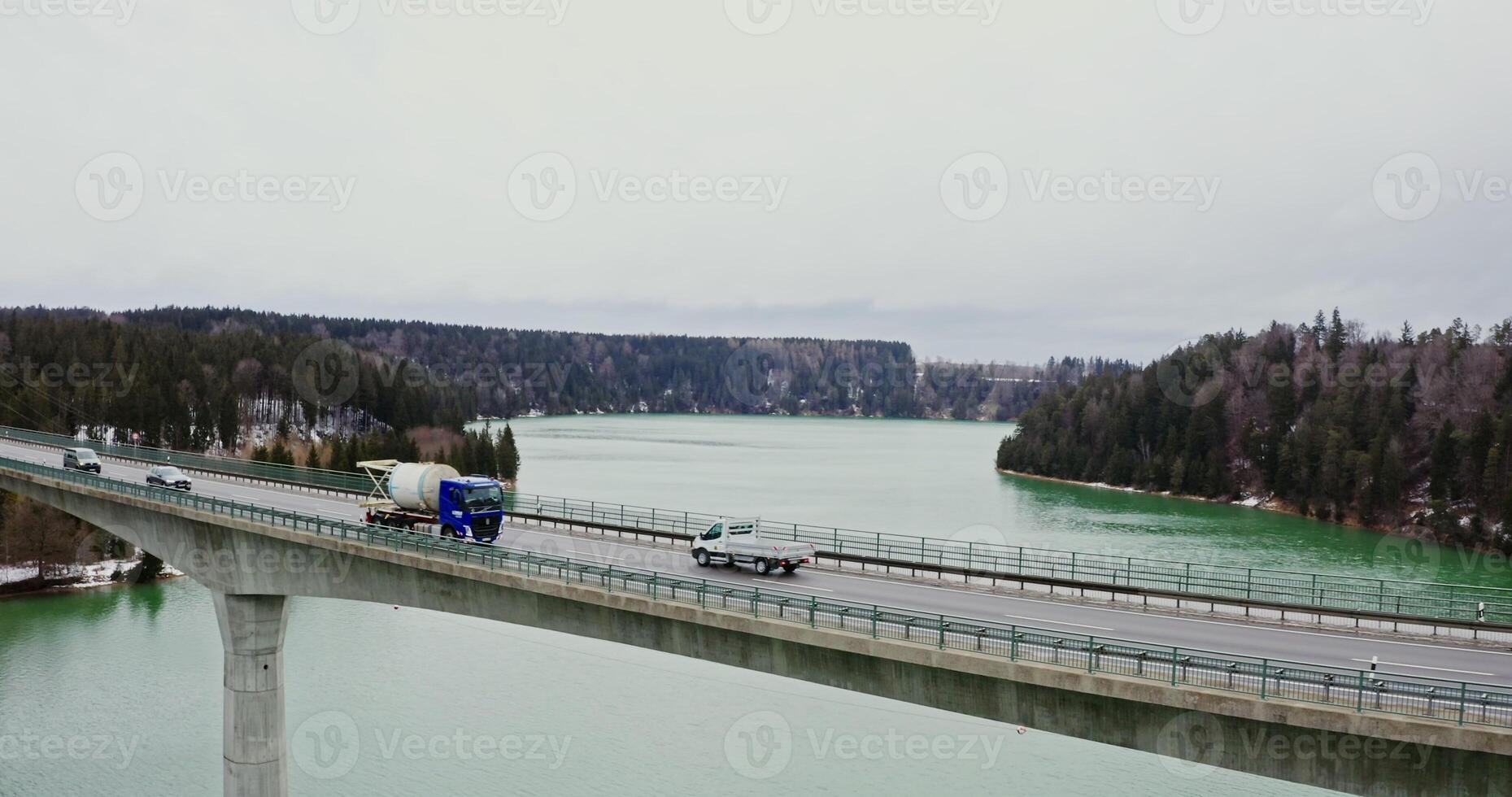 A view of a narrow automobile bridge thrown across the river to the hills overgrown with spruce forest, filming on a winter day photo