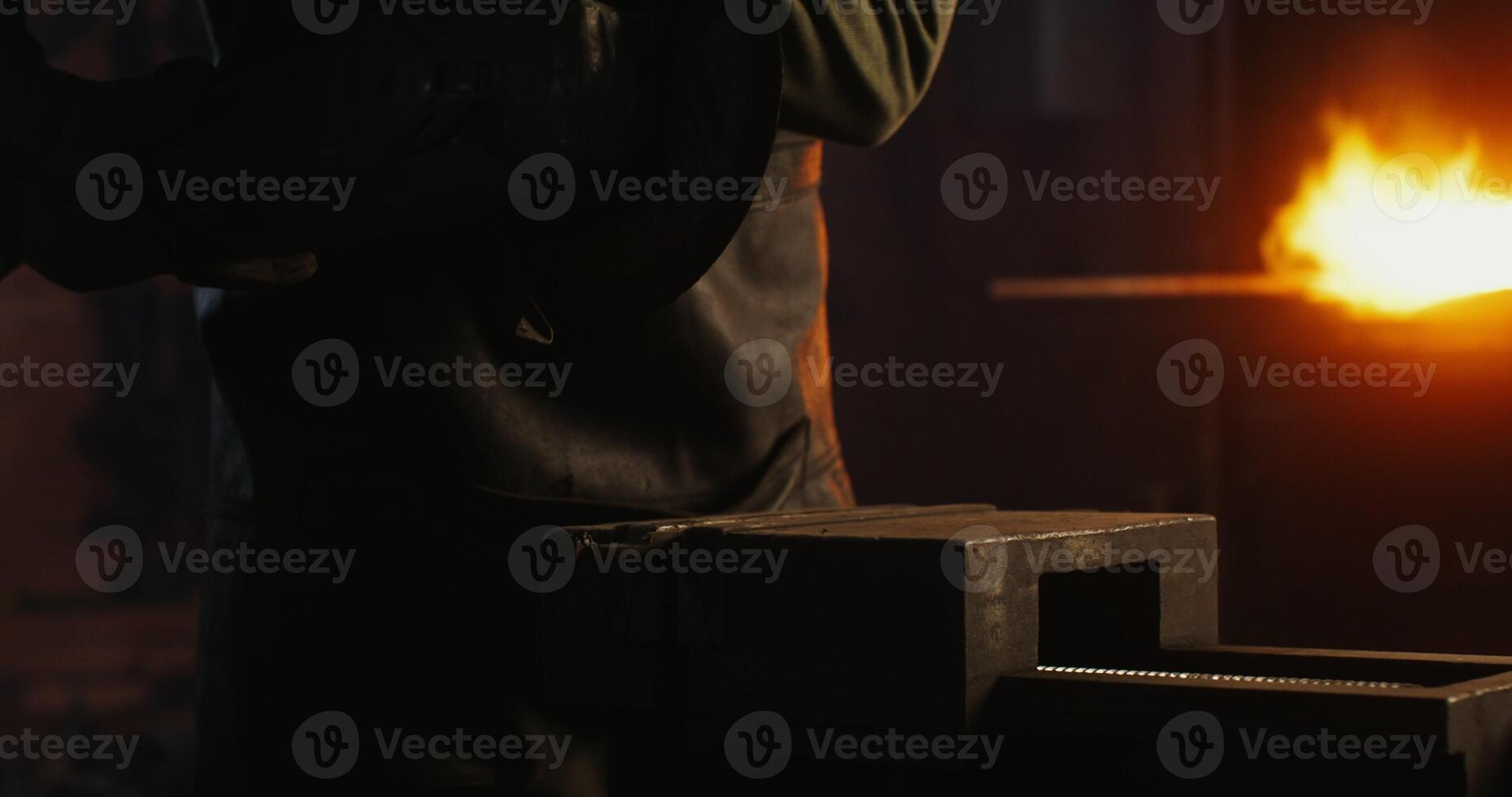 A blacksmith in protective equipment saws off part of a metal stick using an angle grinder, metal sparks fly in different directions, close up, no face, unrecognizable person. 4k , red komodo photo