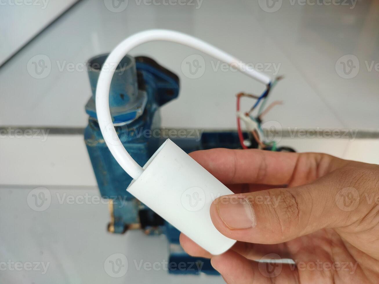 Hand holding and checking electric motor capacitor. Single phase motor capasitor photo